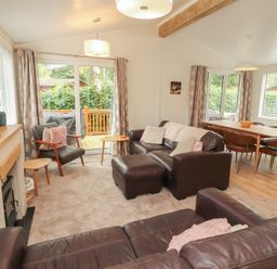 A living room with a sofa and dining area at Beech Grove Lodge, Glade 17, Fallbarrow Park near Bowness on Windermere