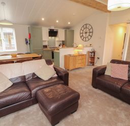 A living room with a sofa and dining table at Beech Grove Lodge, Glade 17, Fallbarrow Park near Bowness on Windermere