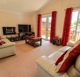 A living room with two sofas red curtains TV and coffee table at Robins Nest in Bowness 71 White Cross Bay near Windermere