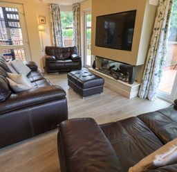 A living room with leather sofas a wall mounted television and glass doors at Thirlmere View Thirlmere 6 White Cross Bay near Windermere
