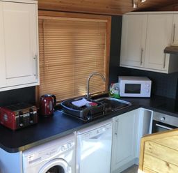 A kitchen with a sink microwave red toaster and kettle washing machine at Glaramara Number 7 Burnside Park near Keswick
