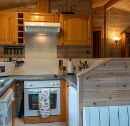 A kitchen with wooden cabinets a white oven a microwave and kitchen utensils at Rivendell Burnside Park Number 14 Burnside Park near Keswick