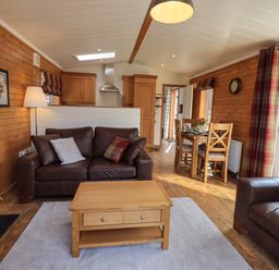 A living room with leather sofas a wooden coffee table and a dining table at Ramblers Rest Lodge Pinewood 22 Limefitt Park near Windermere