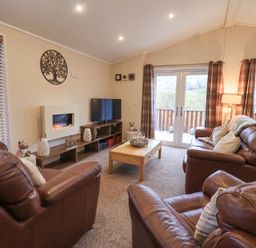 A living room with brown leather sofas a wooden coffee table a wall-mounted fireplace and a television at Horseshoe Lodge Wansfell 5 Limefitt Park near Windermere
