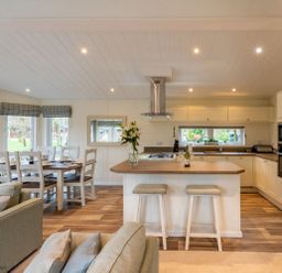A kitchen with a wooden island and two stools next to a dining table with chairs at Langdale Lodge Langdale 21 White Cross Bay near Windermere