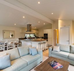 An open plan living room with two sofas a coffee table and a kitchen with a dining table at Langdale Lodge Langdale 21 White Cross Bay near Windermere
