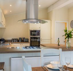 A kitchen with countertop stove oven and dining table with dishes and glasses at Langdale Lodge Langdale 21 White Cross Bay near Windermere