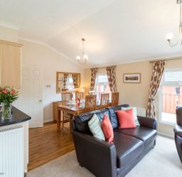 A living room with a black leather sofa and dining table with chairs at Hideaway Lodge Kirkstone 14 Limefitt Park near Windermere