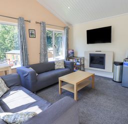 A living room with two sofas a coffee table a mounted television a small fridge and a microwave at Robin View Lodge Beckside 3 Limefitt Park near Windermere