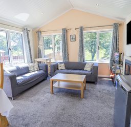A living room with two sofas a coffee table a television and large windows at Robin View Lodge Beckside 3 Limefitt Park near Windermere