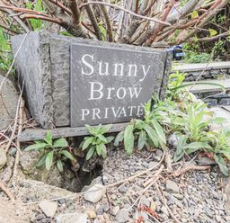 A stone plaque with the words Sunny Brow Private surrounded by plants and rocks at Sunny Brow Lodge Lakeside 5 White Cross Bay near Windermere