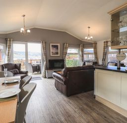 A living room with dining table set with plates and glasses and leather sofas at Sunny Brow Lodge Lakeside 5 White Cross Bay near Windermere