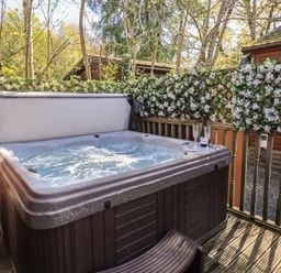 An outdoor hot tub surrounded by flowers at Badgers Hollow Lodge Grasmere 30, White Cross Bay near Windermere