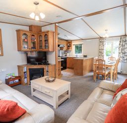 A living room with sofas and a coffee table connected to a kitchen and dining area at Pinehaven Lodge Grasmere 6 White Cross Bay near Windermere
