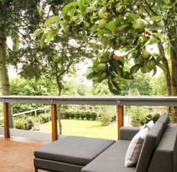 A deck with gray patio furniture and green apples hanging from a tree at Sunnyside in Bircher Common near Yarpole