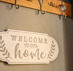 A wall with a welcome sign and decorative metal hooks on a wooden board at Sunnyside in Bircher Common near Yarpole