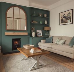 A living room with sofas a wooden coffee table a fireplace and a green accent wall at Fairhaven Dartmouth