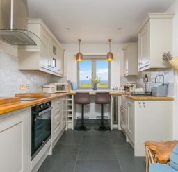 A kitchen with cabinets, countertop, and stools at Scilly Stack in St Just