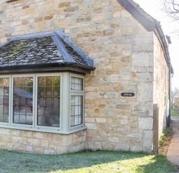 Stone cottage with leaded windows and a small path beside it at Cowfair Cottage in Chipping Campden