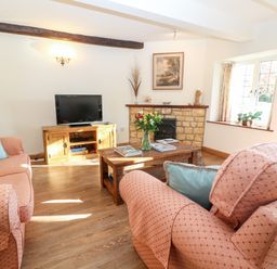 A living room with sofas and a coffee table with flowers at Cowfair Cottage in Chipping Campden