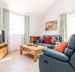 A living room with blue leather sofas and a wooden coffee table at Chy-Whel in Sticker