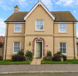 A two story brick house with a green front door and four windows with white shutters at Coral House in Overstrand