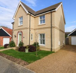 A two story house with a pitched roof a green front door and a driveway with garages at Coral House in Overstrand