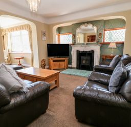 A living room with leather sofas a wooden coffee table a television and a fireplace at Harbour Lights in Torquay
