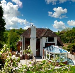 A house with a conservatory and garden surrounded by trees and fields at Harbour Lights in Torquay