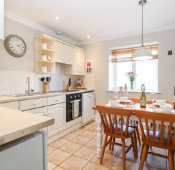A kitchen with a dining table set for four next to a window at Farm View Lodge in Painswick