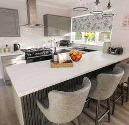 A kitchen with a bar counter and stools at Westwinds in Tenby