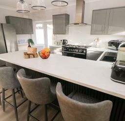 A kitchen with a kitchen island and bar stools at Westwinds in Tenby