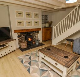 A living room with a wood burning stove tv cabinet coffee table and sofa at Sea View in Newport Pembrokeshire