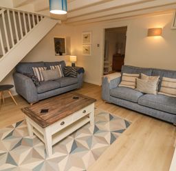 A living room with two blue sofas a wooden coffee table and a patterned rug at Sea View in Newport Pembrokeshire