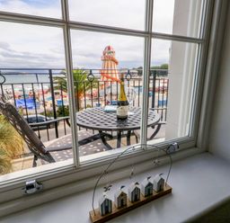 A window view showing a table with a bottle and beach outside at 4 The Beaches Weymouth