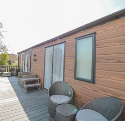 An outdoor deck with wicker chairs and a wooden wall at Dreams & Streams in Bockenfield Country Park near West Thirston
