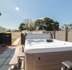 An outdoor hot tub with bubbling water next to a small table with wine and glasses at Dreams & Streams Bockenfield Country Park near West Thirston