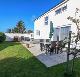 A backyard with a patio table and chairs umbrella and potted plants next to a white house at Beach Reach in Valley