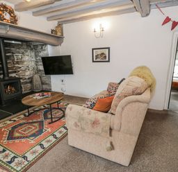 A living room with a sofa and coffee table at Orsedd Wen Farmhouse in Betws-Y-Coed