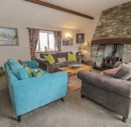 A living room with sofas and a fireplace at Orsedd Wen Cottage in Betws-Y-Coed