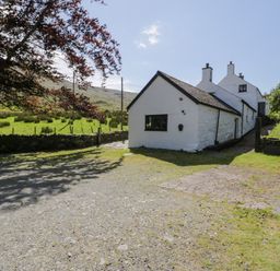 A house with a gravel path and trees at Cwm in Capel Curig