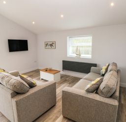 A living room with two gray sofas and a wall-mounted television at Caban Y Mor in Amroth near Saundersfoot