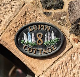 A nameplate for Lupin Cottage 8 on a stone wall at Lupin Cottage in Akeld near Wooler