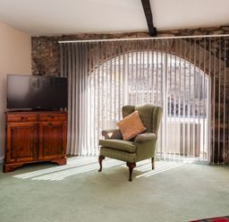 A living room with a television and an armchair at Lupin Cottage near Wooler