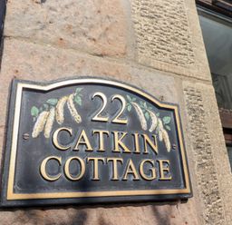 A house number plaque 22 Catkin Cottage mounted on a stone wall beside a window at Catkin Cottage Akeld near Wooler