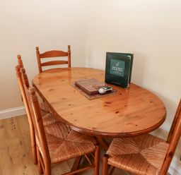 A wooden dining table with six chairs and a book and items on the table at Catkin Cottage Akeld near Wooler