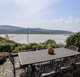 An outdoor area with a table and chairs overlooking a river at 5 Porkington Terrace in Barmouth