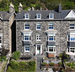 A stone house with windows and outdoor furniture at 5 Porkington Terrace Barmouth