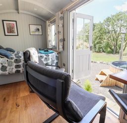 A bedroom with two single beds a chair and an open door leading outside to a wooden hot tub at The Moorhen Retreat in Nantmawr near Trefonen