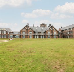 A large brick building with multiple windows and a green lawn in front at 21 The Rest in Porthcawl